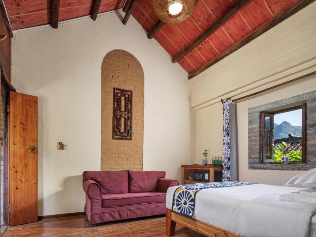 WildChina introduces the Best Boutique Hotels in China (2024) - A guest room with a view of the Karst mountains beyond Qing Dynasty rooftops.