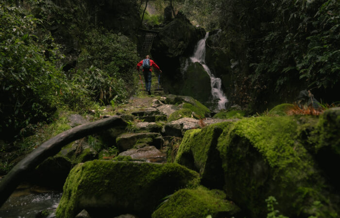 A hiker walking on a stone path next to a waterfall on Songyang ancient trails.