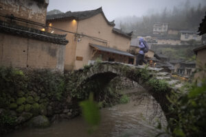 kyleobermann_songyang_selects-24 Hiker crossing a centuries old stone bridge in Songyang, Zhejiang.