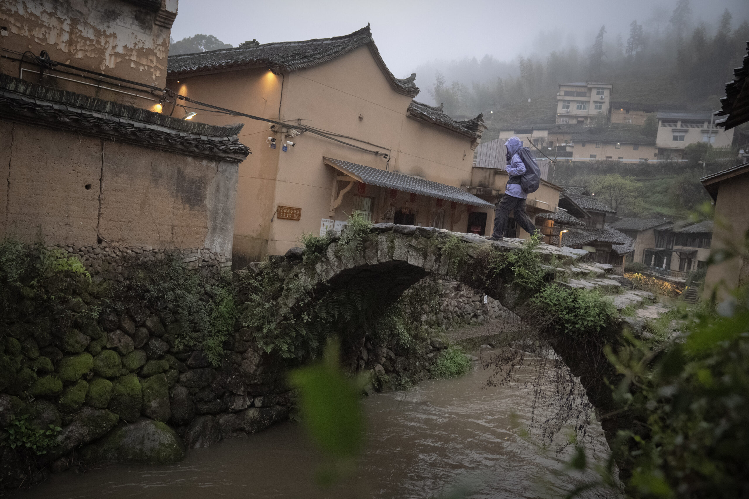 Hiker crossing a centuries old stone bridge in Songyang, Zhejiang.